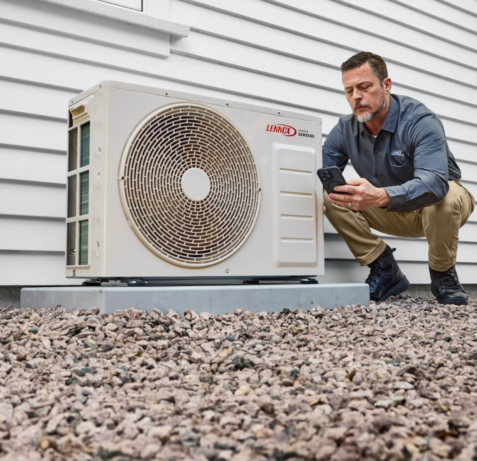 Technicien vérifiant son téléphone lors de l’entretien d’une thermopompe