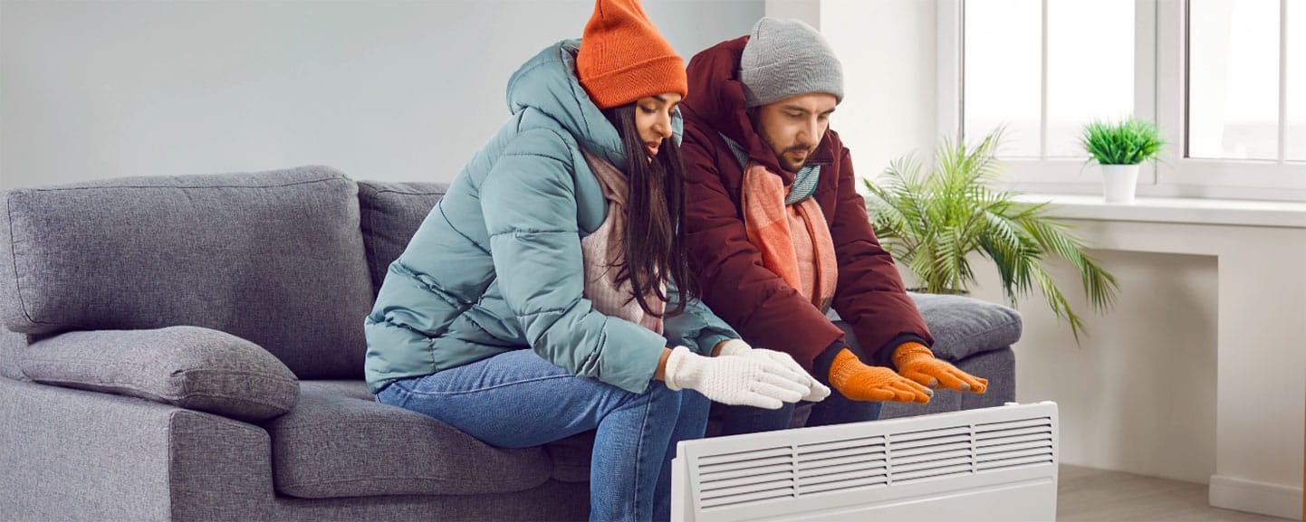 Couple avec mitaines se réchauffant à la maison avec une thermopompe