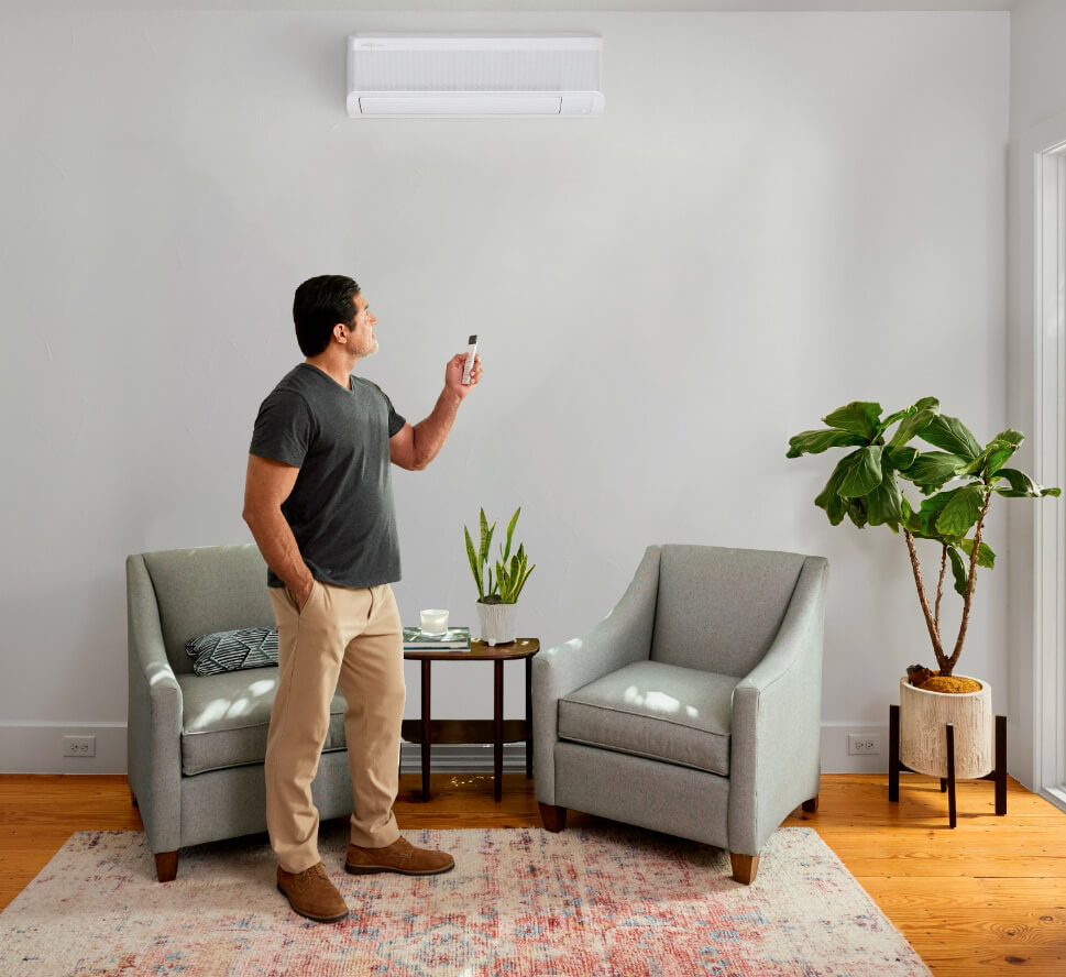 Homme réglant la température d’une thermopompe murale avec télécommande