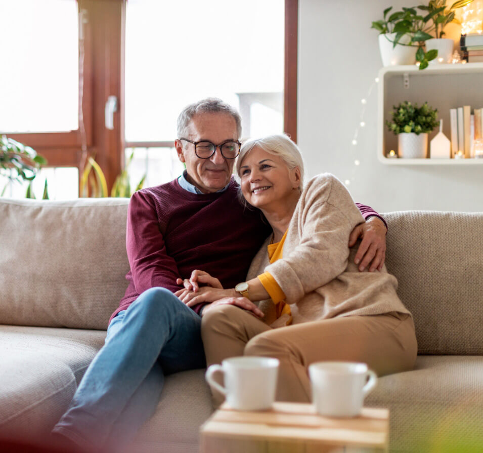 Couple assis sur le divan, se tenant l’un contre l’autre