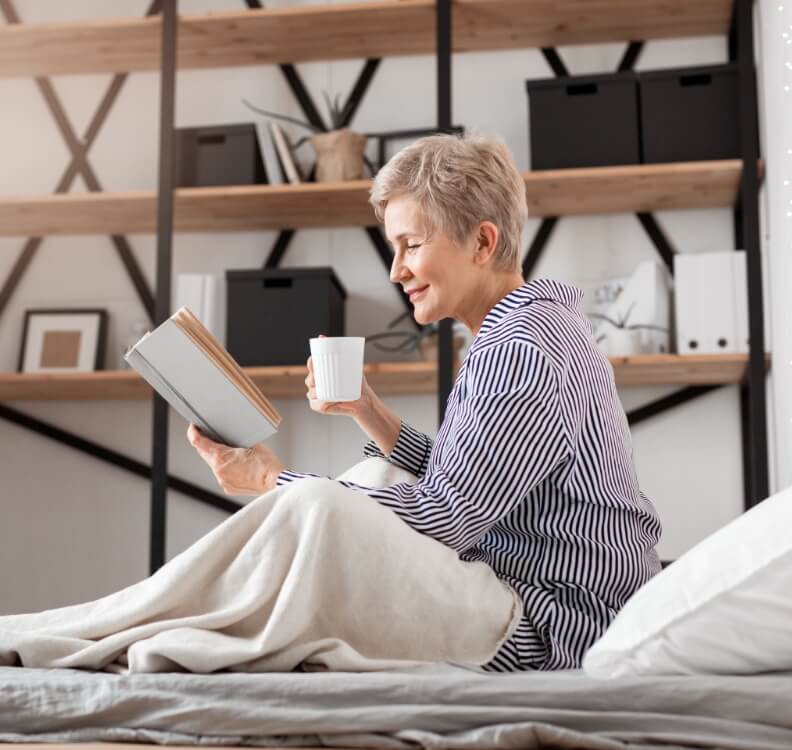 Femme lisant dans son lit avec une tasse de café