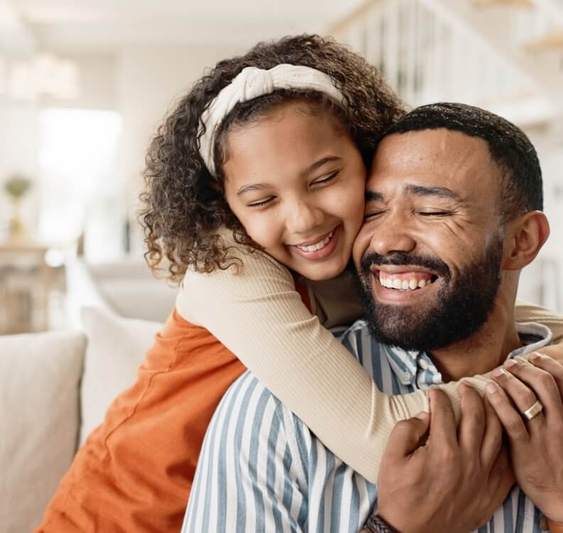 Jeune fille et son père souriants se faisant un câlin à la maison